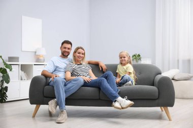 Mutlu aile evdeki kanepede birlikte vakit geçiriyor.