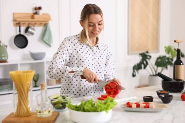 Yemek pişirme süreci. Mutfakta masada biber kesen gülümseyen kadın.