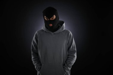 Karanlık arka planda maskeli bir suçlu.