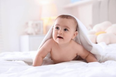 Evde banyo yaptıktan sonra beyaz havluyla tatlı bir bebek.