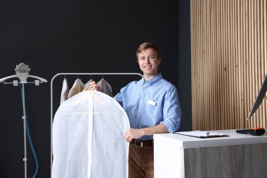 Kuru temizleme servisi. Giysileri içinde tutan mutlu işçi iç mekan örtüsü.