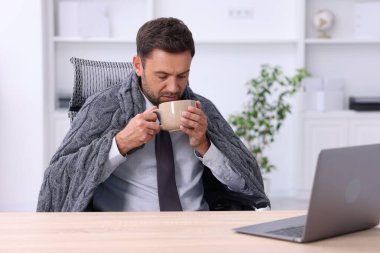 Klima. Ofiste bir bardak sıcak içeceği olan adam soğuk sıcaklıktan muzdarip.