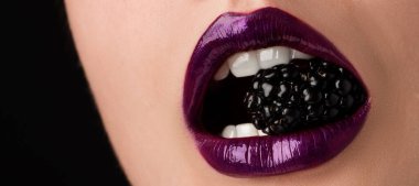 Güzel dudaklı kadın makyajı ve siyah arkaplanda böğürtlen, yakın plan.