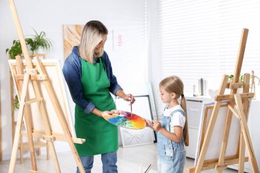 Meslek seçimi. Anne kızına stüdyoda resim yapmayı öğretiyor.