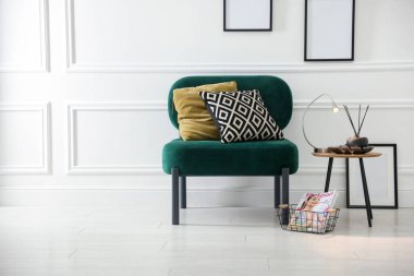 Şık lamba, sazlık dağıtıcı ve koltuk kenarında yastıklı dergi.