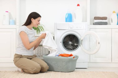 Çamaşır makinesinin yanında çamaşır makinesi olan bir kadın.