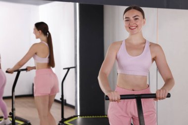 Spor salonundaki aynanın yanındaki trambolinde gülümseyen kadın. Metin için boşluk