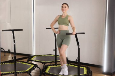 Spor salonundaki trambolinde gülümseyen kadın.