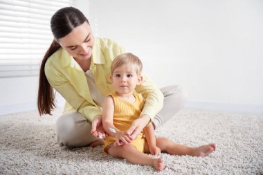 Anne evde bebeğinin koluna krem sürüyor. Metin için boşluk