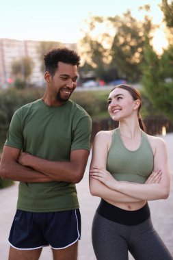 Gülümseyen koşucular dışarıda çapraz kollarla poz veriyorlar.