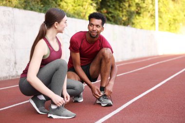 Stadyumda ayakkabı bağcıklarını bağlayan koşucular. Metin için boşluk