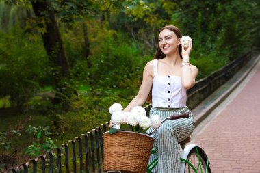 Dışarıda elinde çiçeklerle bisiklete binen bir kadın. Metin için boşluk