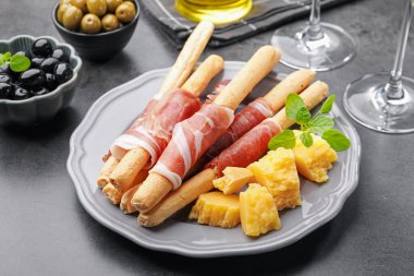 Grissini ekmeği jambonlu, peynirli ve zeytinli, gri masada, yakın plan.