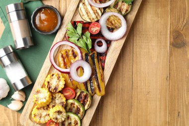 Vejetaryen barbeküsü. Lezzetli ızgara sebzeler, baharatlar ve ahşap masa üzerindeki sos, düz yatak. Metin için boşluk