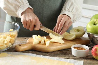 Elmalı turta yapıyorum. Mutfaktaki ahşap masada taze meyve kesen kadın, yakın plan.