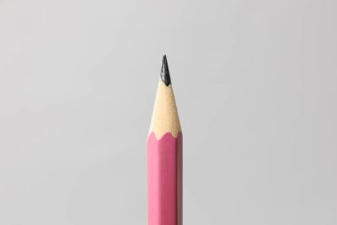 Gri arkaplanda keskin bir grafit kalem, yakın plan.