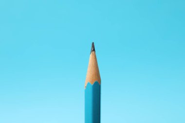 One sharp graphite pencil on light blue background, closeup