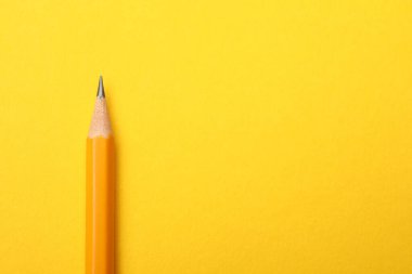 Sarı arka planda keskin bir grafit kalem, üst manzara. Metin için boşluk