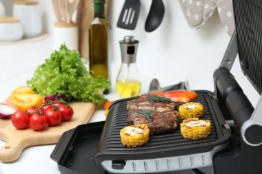 İçerideki beyaz tezgahta lezzetli et, sebze ve yağlı ızgara, yakın plan.