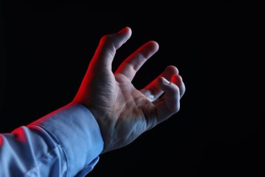 Siyah arka planda bir şey tutan adam, yakın plan.