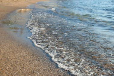 Güzel dalgalı deniz ve kumlu sahil, yakın çekim.