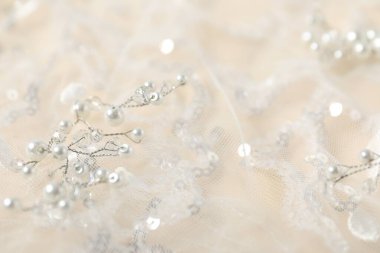 Bej arka planda pulları ve incileri olan güzel dantel kumaş, yakın plan.