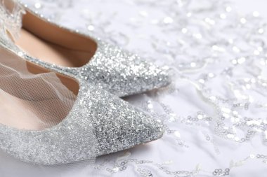 Beyaz arka planda pulları olan güzel ayakkabılar ve dantel kumaş, yakın plan.