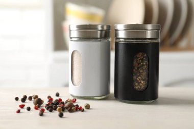 Mutfaktaki hafif ahşap masada tuzluklar, biberlikler ve biberlikler, yakın plan.