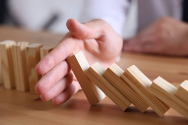 Risk. Tahta masada domino efektini durduran adam, yakın plan.