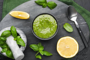 Lezzetli yeşil pesto kasede, fesleğen yaprakları ve limon siyah masada, üst tarafta.