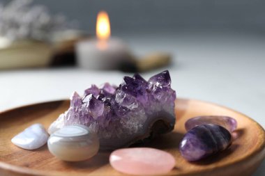 Farklı güzel değerli taşlar ve yanan mum Masada, yakın plan