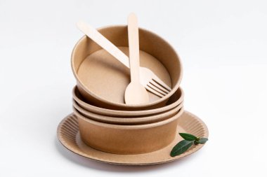 Beyaz arkaplanda tek kullanımlık eşyalar ve yeşil yapraklar, yakın plan