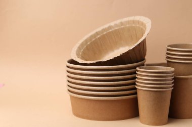 Koyu bej arka planda tek kullanımlık sofra takımı, yakın plan. Metin için boşluk