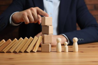 Risk. Masasında tahta küpleri, blokları ve insan figürleri olan, seçici odaklı bir adam.