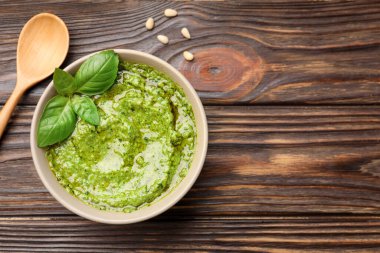 Tabakta taze pesto sosu ve tahta masada kaşık, üst manzara. Metin için boşluk
