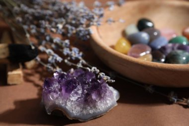 Kahverengi arka planda farklı güzel değerli taşlar ve lavanta çiçekleri, seçici odak