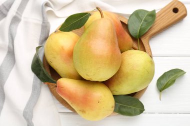 Taze armutlar ve yeşil yapraklar beyaz ahşap masada, düz yatıyordu.