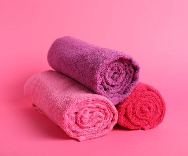 Pembe arka planda yuvarlanmış temiz havlular, yakın plan.
