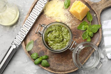 Taze pesto sosu kavanozda, rende ve malzemeler gri desenli masada, düz yerde.