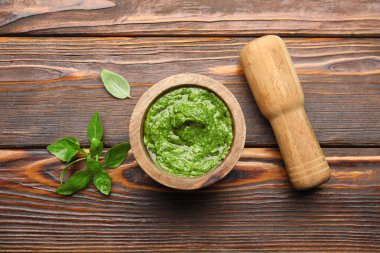 Havanda taze pesto sosu, ahşap masa üzerinde tokmak ve fesleğen yaprakları, düz yatıyordu.