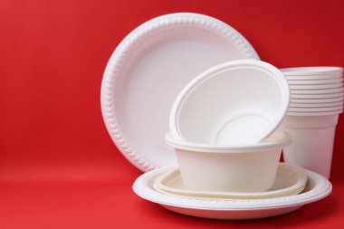 Kırmızı arka planda tek kullanımlık plastik sofra takımı, yakın plan. Metin için boşluk