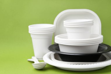 Açık yeşil arkaplanda tek kullanımlık plastik sofra takımı, yakın plan