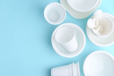 Açık mavi arka planda tek kullanımlık plastik sofra takımı, düz. Metin için boşluk