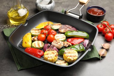 Gri masada ızgara sebze ve baharatlı tava, yakın plan.