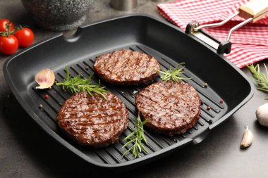 Izgara köfteli tava, domates ve baharatlar gri masada, yakın plan.