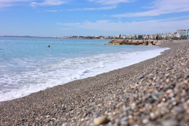 Dalgalı deniz manzarası ve kumsaldaki çakıl taşları.