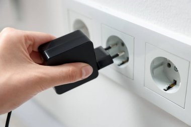 USB adaptörünü kabloyla beyaz duvardaki elektrik prizine takan kadın, kapat