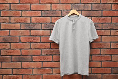 Kırmızı tuğla duvara karşı gri tişörtlü bir askı. Tasarım için model