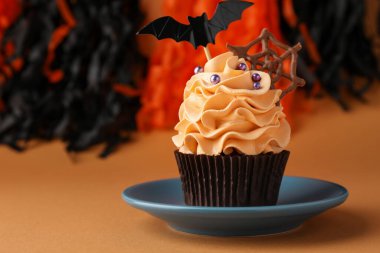 Çikolata ağlı enfes kek, turuncu masa üzerine serpiştirilmiş yarasa süsü ve renkli arka plan, yazı için yeri olan yakın plan. Cadılar Bayramı