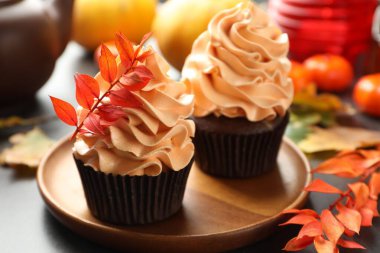 Gri masa üzerinde kırmızı yapraklı dalları olan lezzetli kekler, yakın plan. Sonbahar atmosferi